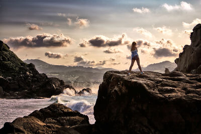 Rear view of man standing on rock at beach