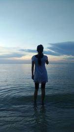 Rear view of woman standing on sea against sky