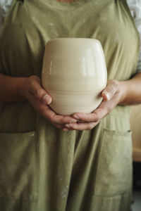 Midsection of woman holding ceramic in workshop
