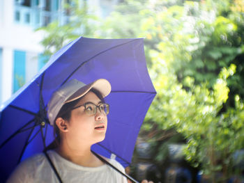 Woman with purple umbrella looking up