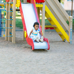 Cute girl sitting in slide at playground