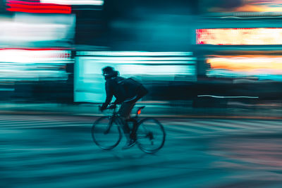 Man riding bicycle on city at night