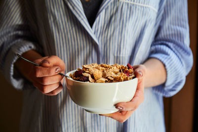 Young woman having breakfast next to a window at home