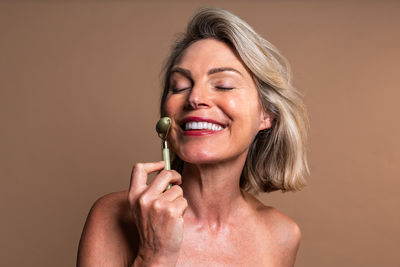 Portrait of young woman applying make-up against wall