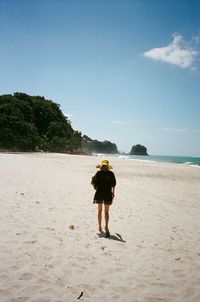 Rear view of man standing on beach against sky