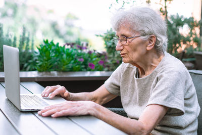 Old woman using laptop on terrace