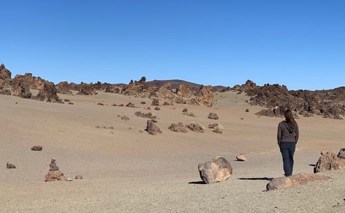 Rear view of woman standing at desert against clear sky