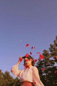 Woman standing by red tree against sky