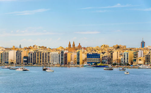 Sailboats in sea against buildings in city