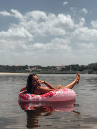 Young woman relaxing on inflatable ring over lake