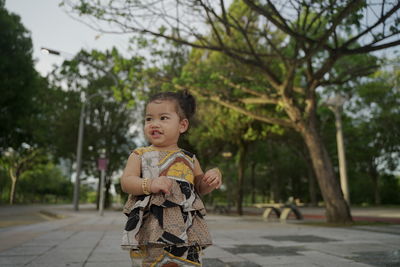 Cute boy looking away against trees