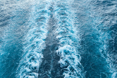 Stormy foam and a ship's track on the blue sea water.