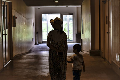 Rear view of mother and son walking in corridor