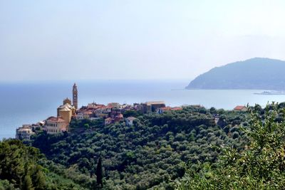 Buildings on mountain by sea against sky