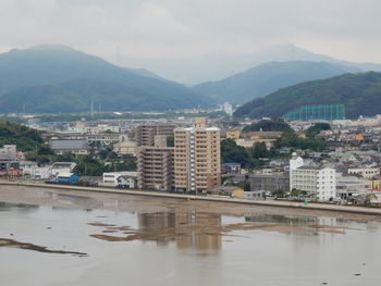 River by buildings in city against sky