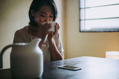 Woman drinking coffee while sitting at home