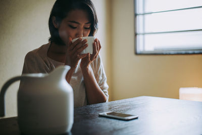 Young woman drinking coffee cup on table