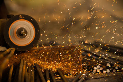 Close-up of grinder cutting metal rods at workshop