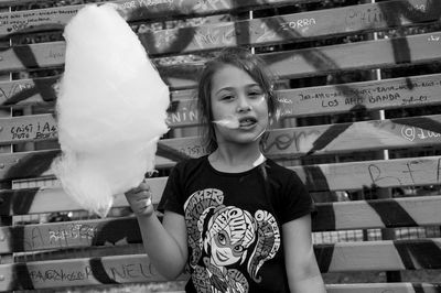 Portrait of girl with cotton candy standing against wall