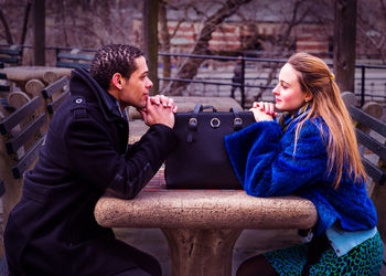 Two friends are sitting outside to chat in cold winter