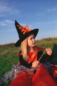 Young woman wearing hat while sitting on field