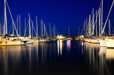 Sailboats moored in harbor reflected in the sea at dusk 