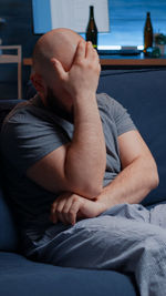 Midsection of man sitting on bed at home