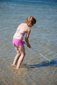 Full length of boy standing in sea