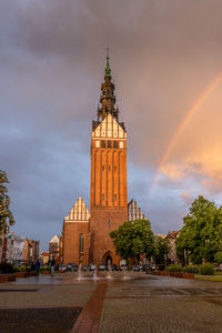 Church tower amidst buildings against sky during sunset in the city elblag.