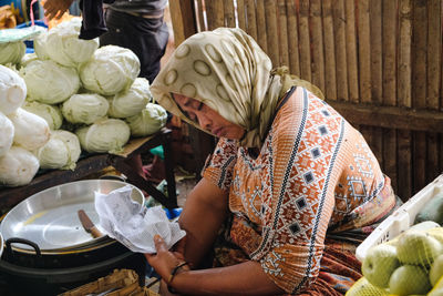 Tired woman sleeping while sitting at market stall