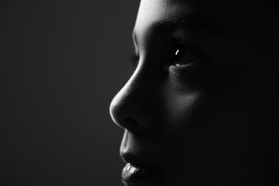 Close-up of young woman against black background