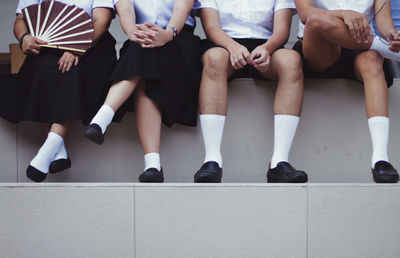 Low section of friends sitting on steps in school