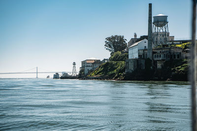 View of buildings by sea against clear sky