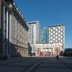 Buildings in city against clear blue sky