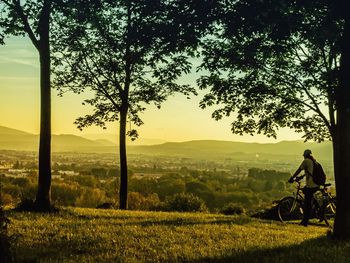 Man riding bicycle on field against sky