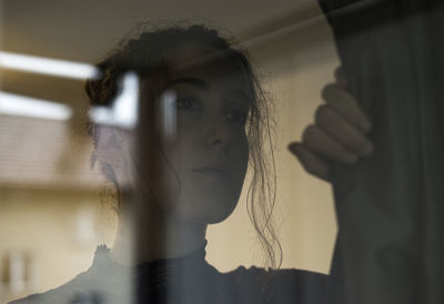 Close-up of young woman looking through window