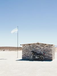 Motorcycle parked by built structure against clear sky