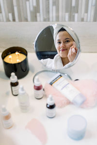 Woman looking at her self in the mirror and doing skin care