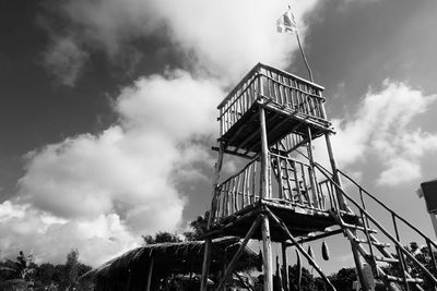 Low angle view of ferris wheel against cloudy sky