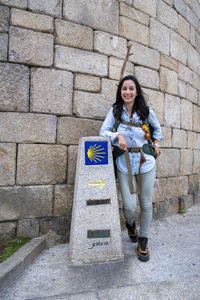 Portrait of young woman standing against brick wall