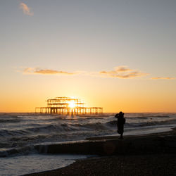 Silhouette people on beach against sky during sunset