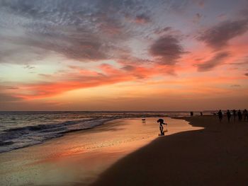 Silhouette people at beach against sky during sunset