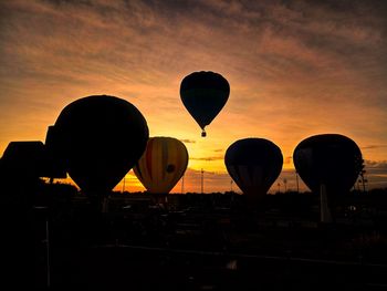 Silhouette hot air balloon against orange sky