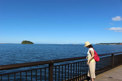 Woman standing on promenade by sea against sky