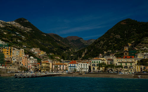 Buildings by sea against sky