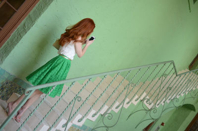 Side view of woman using mobile phone on staircase