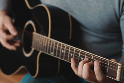 Midsection of man playing guitar