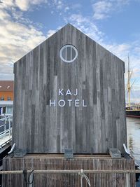 Arrow sign on wooden bridge against sky