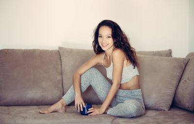 Portrait of smiling young woman sitting on sofa at home