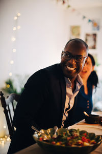 Portrait of smiling man sitting on table at restaurant